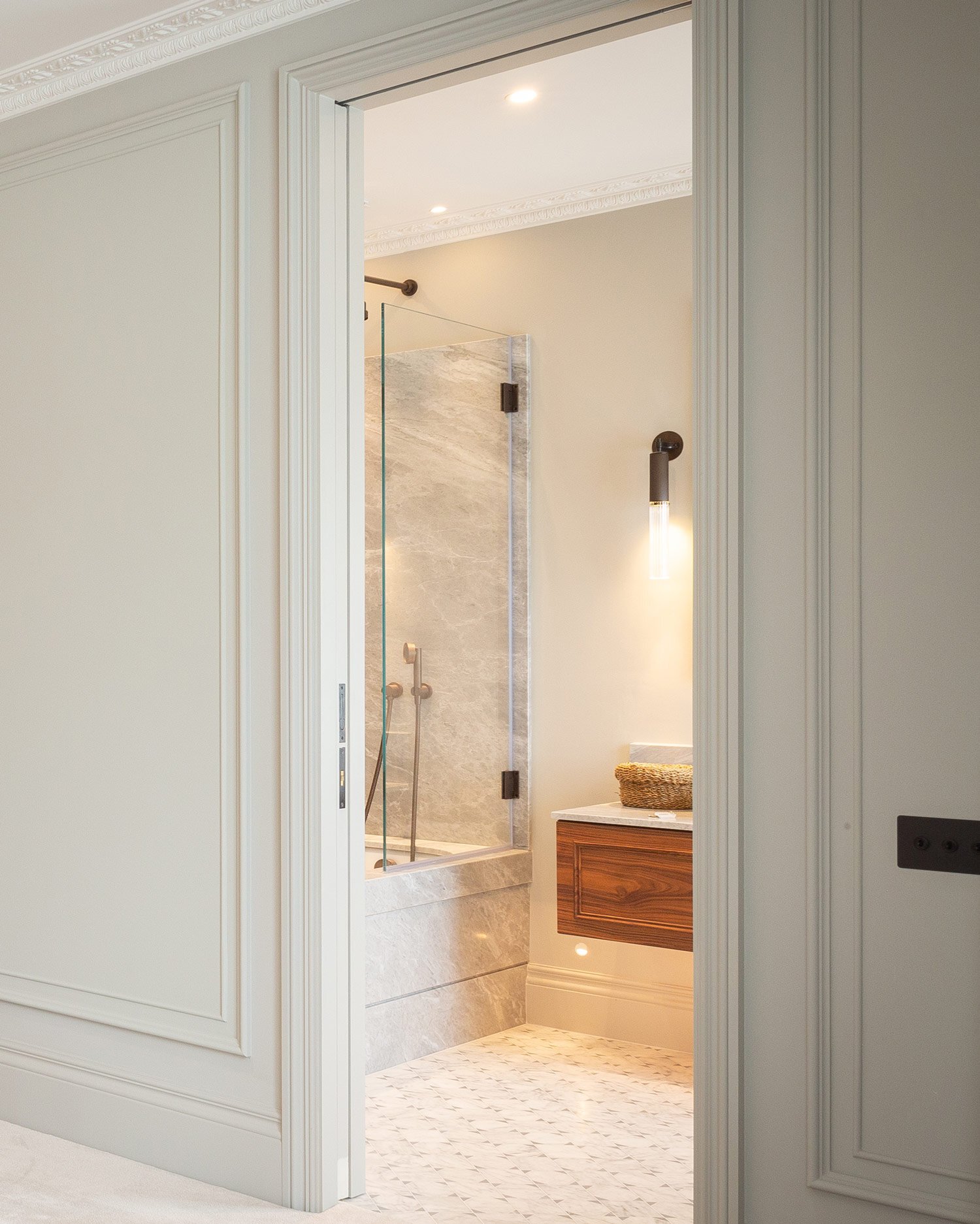 An ensuite bathroom with a sliding timber door in a London townhouse by Layzell Architects