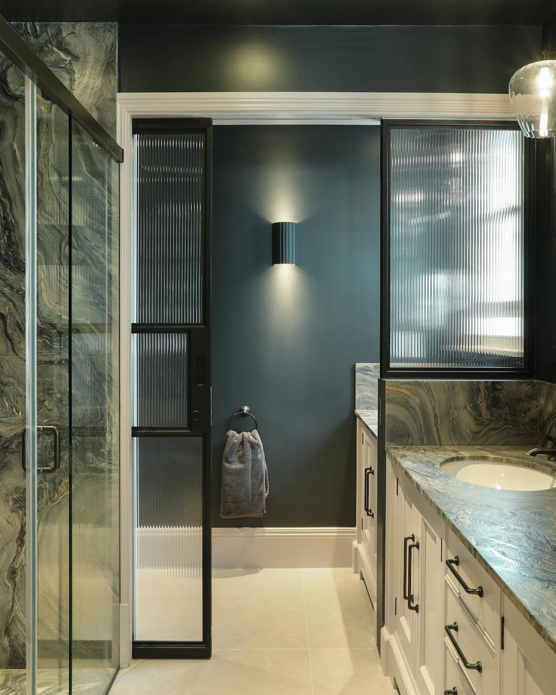a luxury bathroom designed by Icon Architects features a sliding steel glazed door with fluted glass