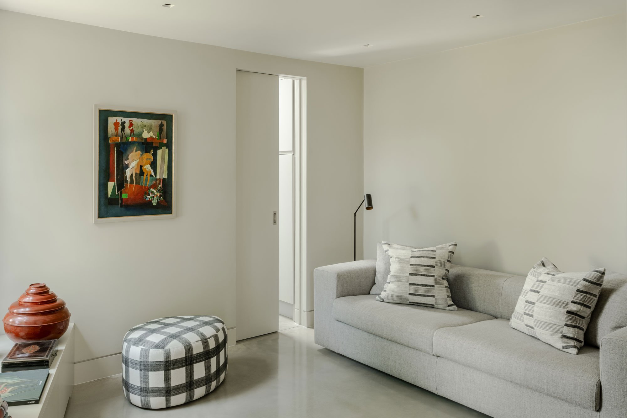 a fire rated pocket door can be seen sliding out of a white wall to create a minimal interior in a living room
